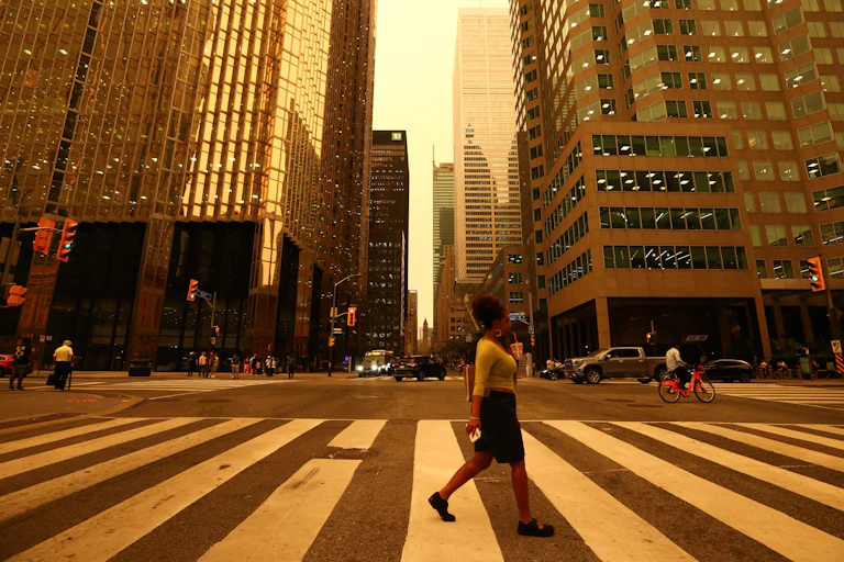 People walk in downtown Toronto, which looks yellow from the wildfire.