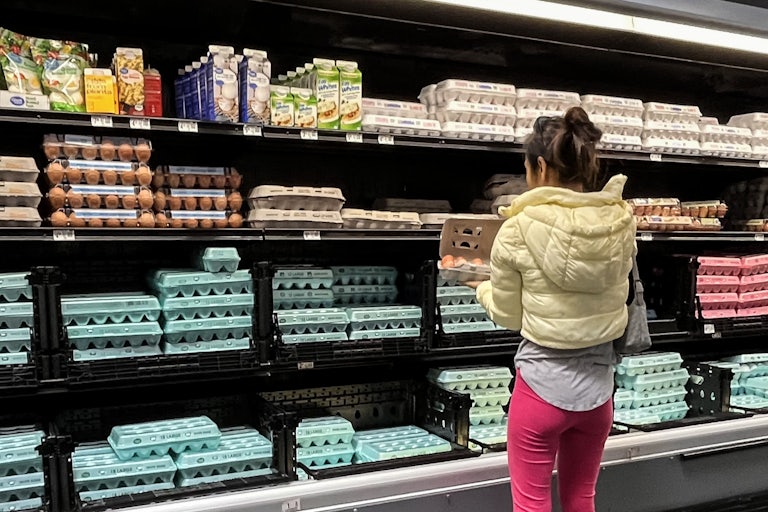 A woman open a carton of eggs in the egg section at a grocery store.