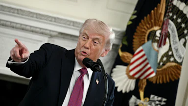 Donald Trump at a podium speaking and pointing
