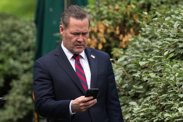 Mike Waltz looks down at his phone.