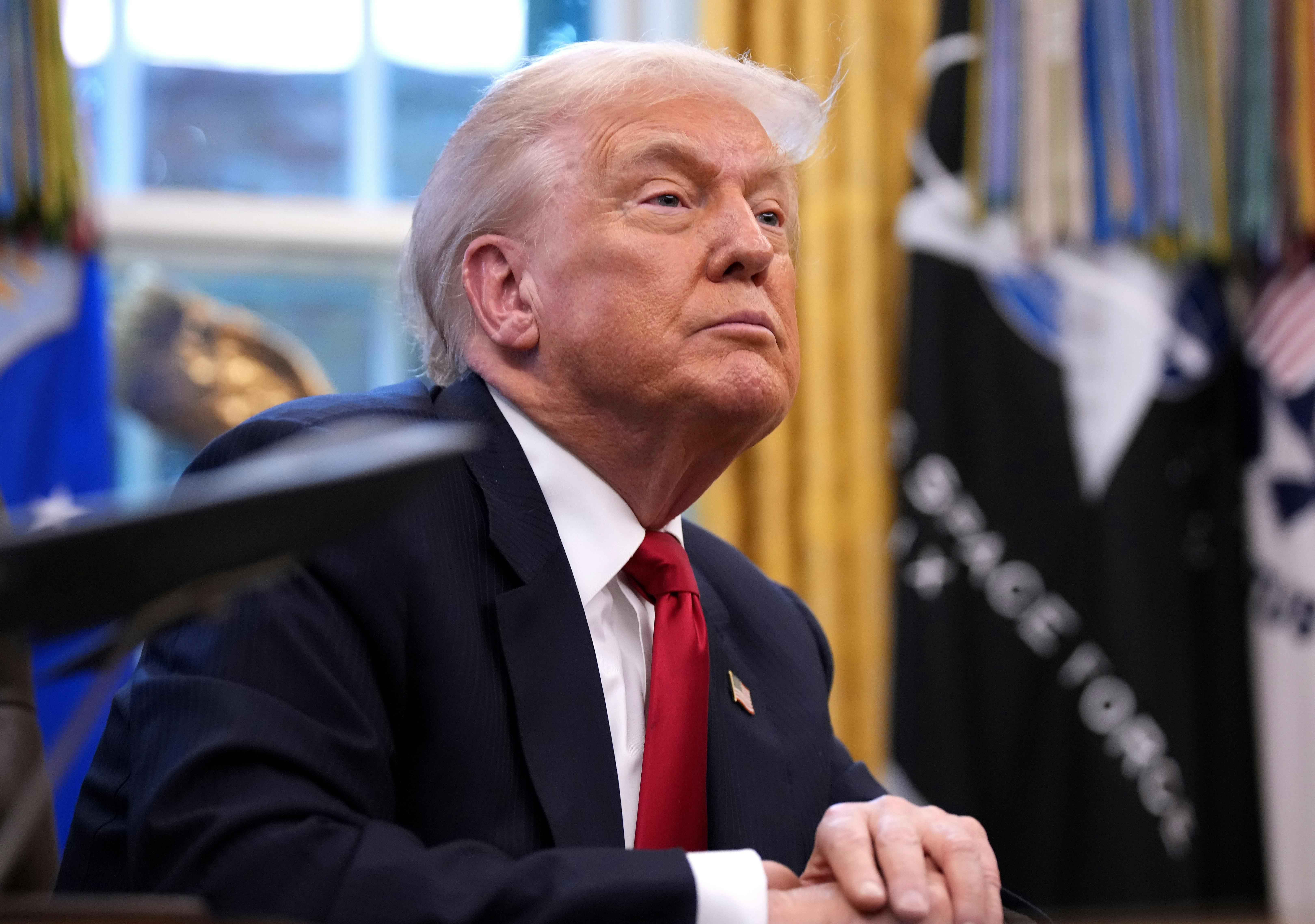 Donald Trump sits at his desk in the Oval Office of the White House.