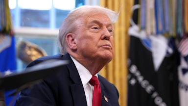 Donald Trump sits at his desk in the Oval Office of the White House.