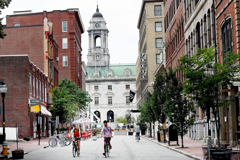 People ride bicycles on a street in Old Orchard Beach, Maine