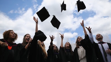 Graduates throw their mortarboards into the air.