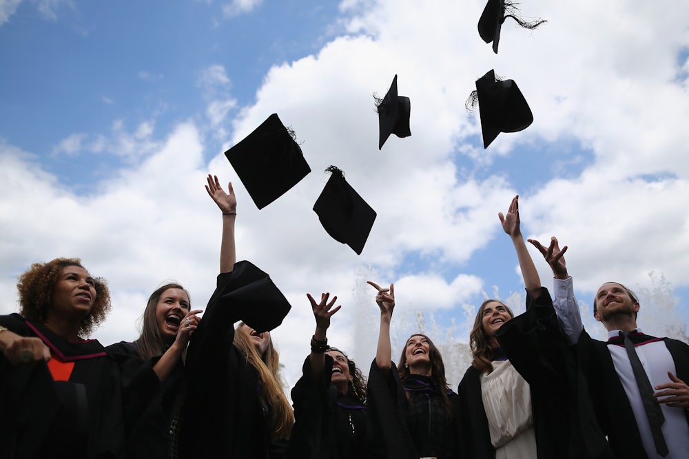 Graduates throw their mortarboards into the air.