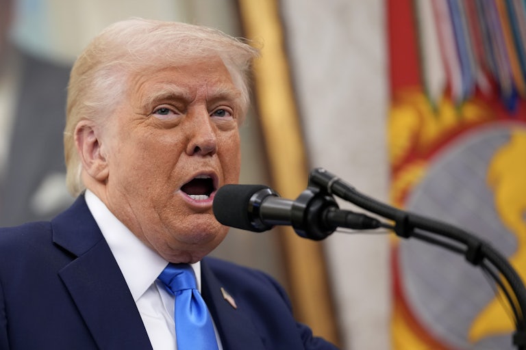 Donald Trump speaks into a microphone in the Oval Office