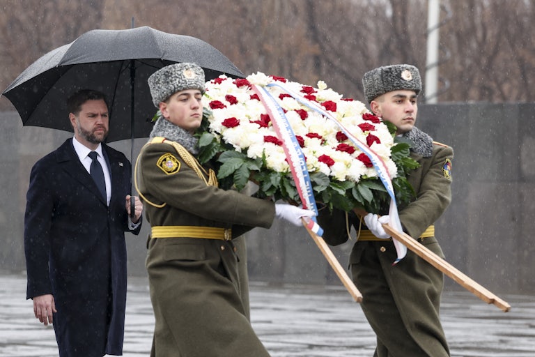 Vice President JD Vance carries an umbrella and walks behind two soldiers carrying a large wreath at the Armenian Genocide Memorial in Yerevan, Armenia.