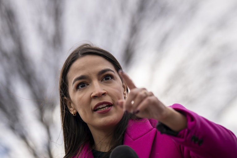 Alexandria Ocasio-Cortez holds up one index finger, as if to make a point o r shame someone