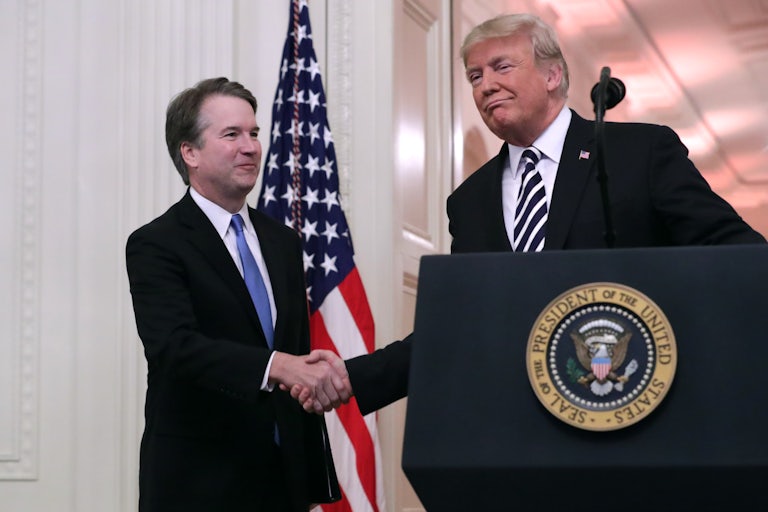 Donald Trump stands at the presidential podium and shakes hands with Brett Kavanaugh