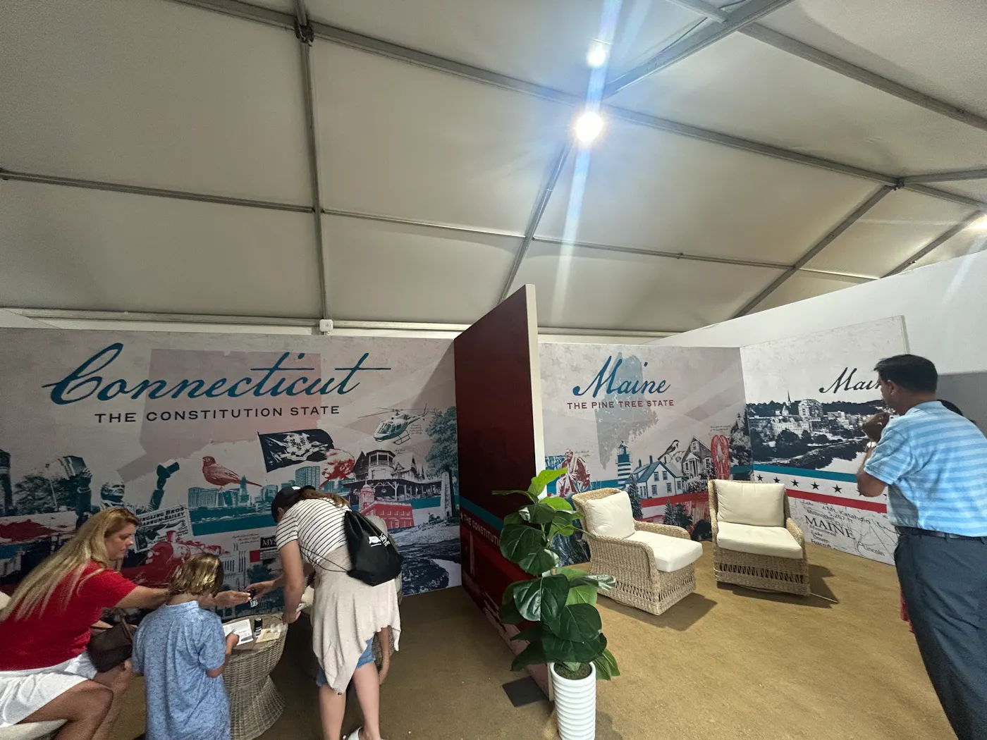 A mother and her two kids stand in an empty Connecticut both. A man observes the empty Maine booth.