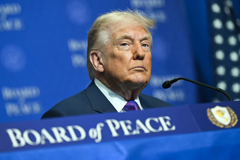 Donald Trump sits at a table during a Board of Peace event
