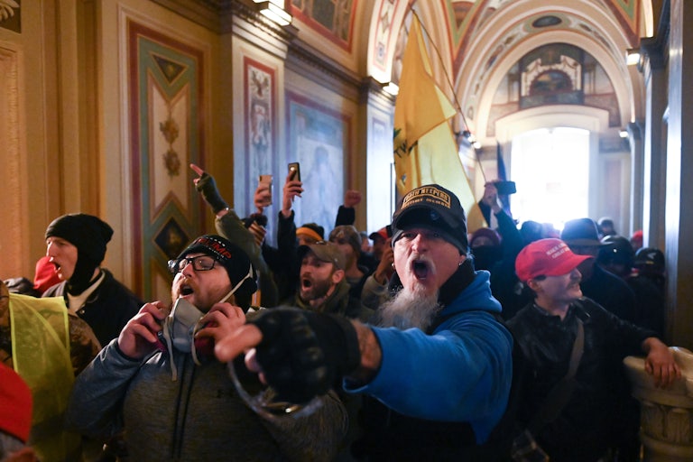 Maskless Trump supporters stand shoulder to shoulder and shout in the U.S. Capitol.