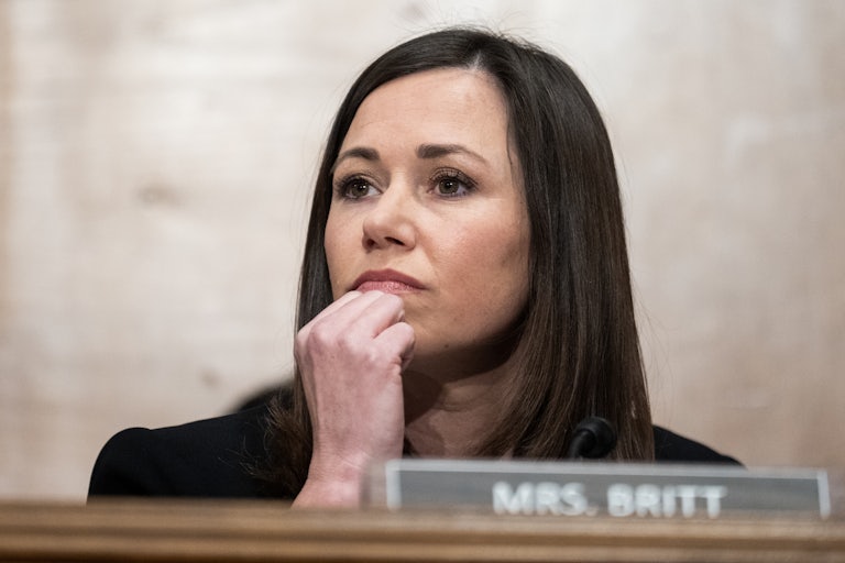Katie Britt rests her chin on her hand. A nameplate before her reads "Mrs. Britt."