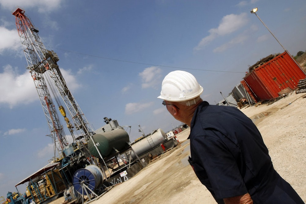 A person in a hard hat looks at machinery.