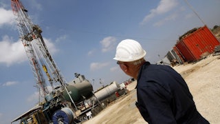 A person in a hard hat looks at machinery.
