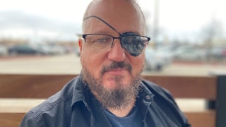 Stewart Rhodes, founder of Oath Keepers, smiles with an eyepatch on.