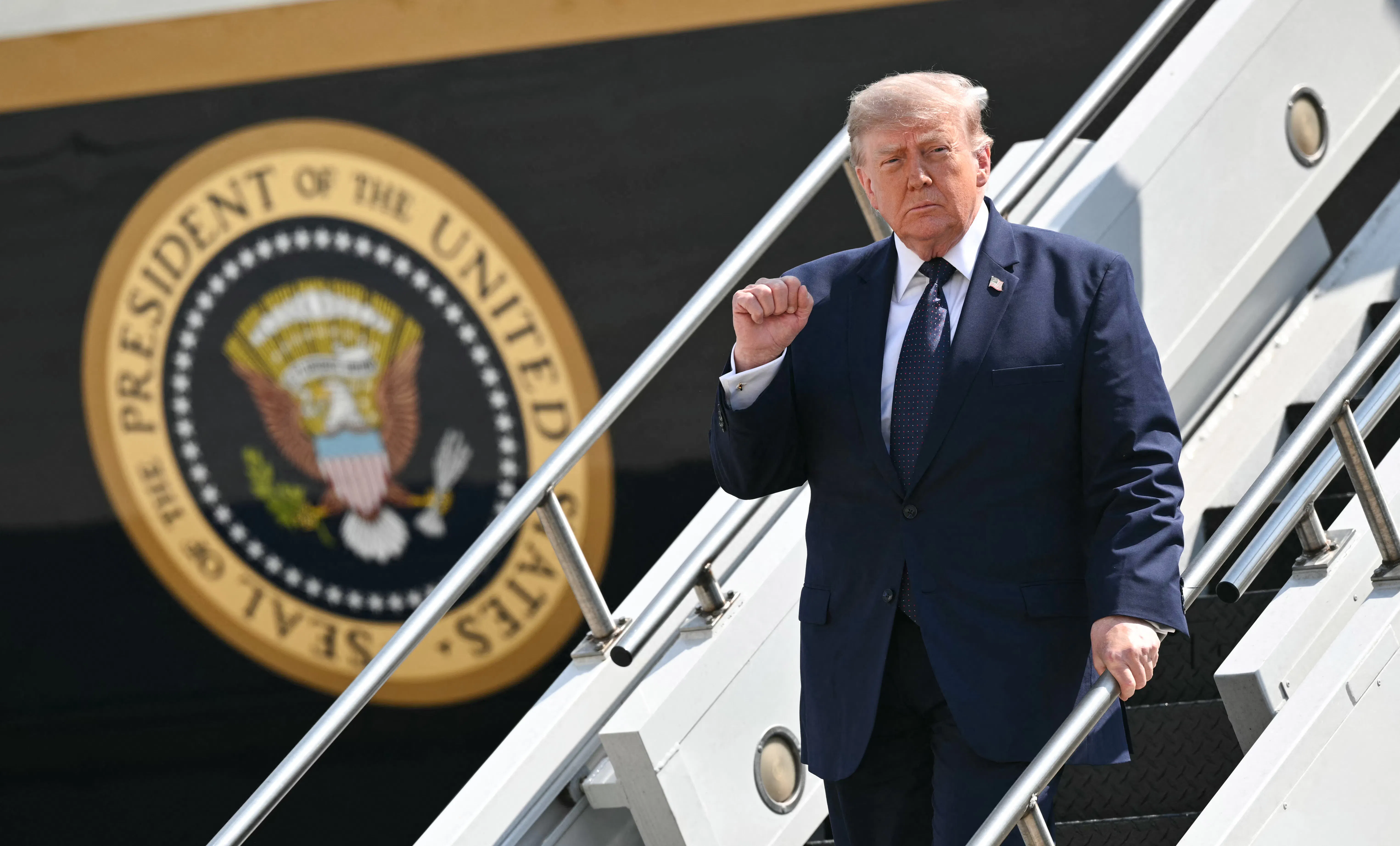 Donald Trump raises his fist while walking down the steps of Air Force One