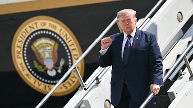 Donald Trump raises his fist while walking down the steps of Air Force One