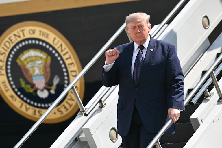 Donald Trump raises his fist while walking down the steps of Air Force One