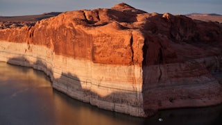 A photograph of Lake Powell showing extreme water loss in the cliffs and with a small boat for scale