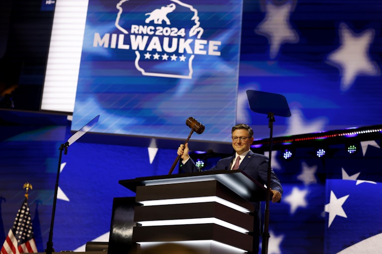 Mike Johnson holds up a giant gavel on stage at the Republican National Convention