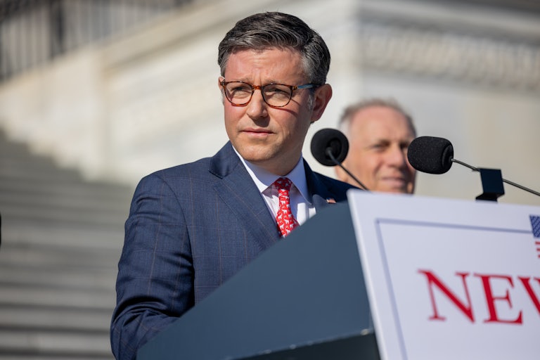 Mike Johnson looks to the side while standing at a podium