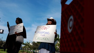 Two demonstrators stand next to a Target shopping cart holding anti-LGBTQ signs.
