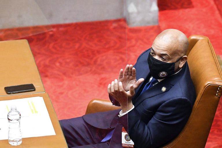 Carl E. Heastie, seated, applauds while wearing a face mask.