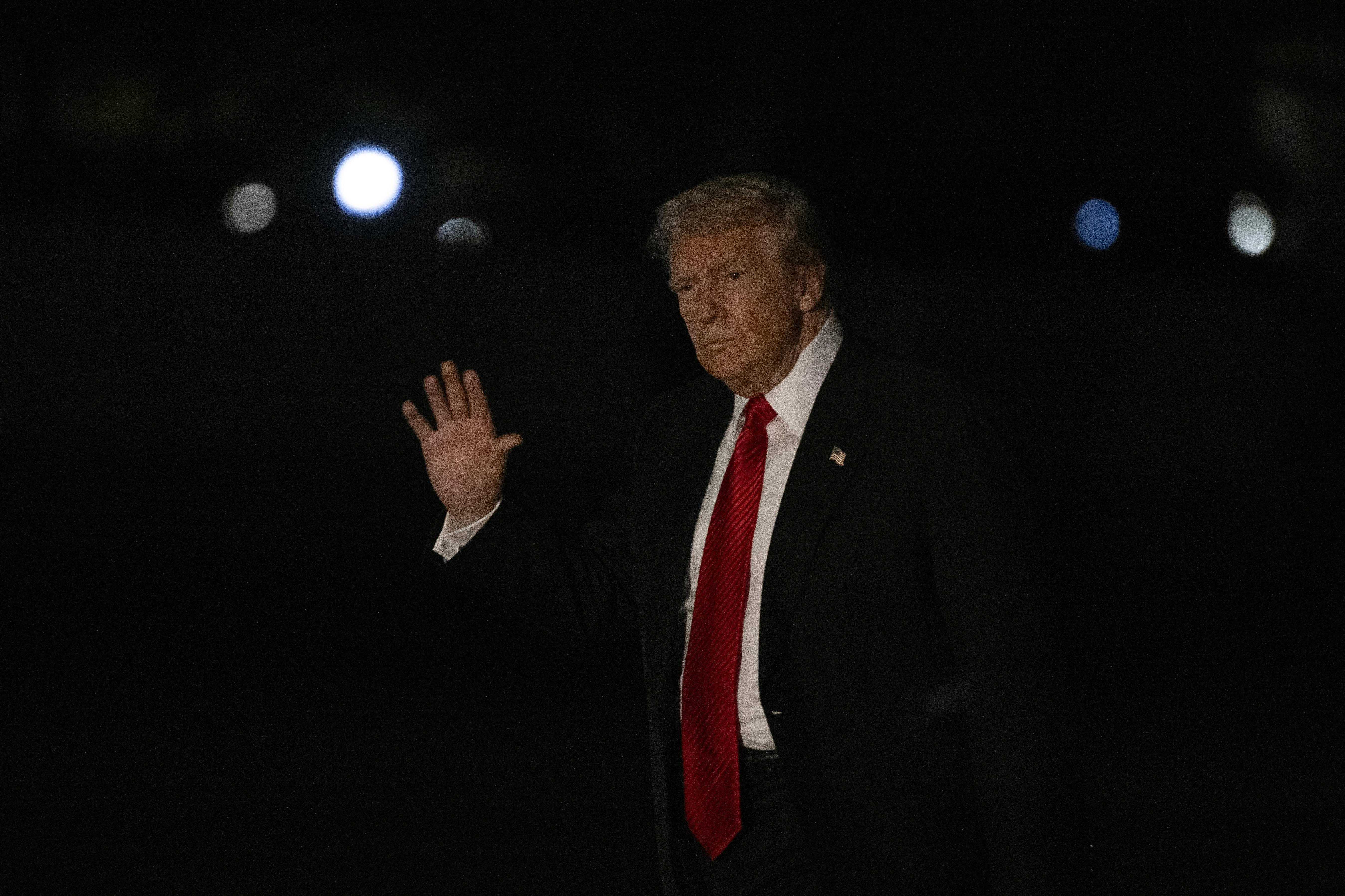 Donald Trump waves while walking outside the White House