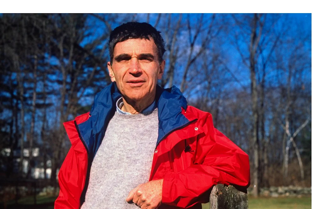Harvard child psychologist Robert Coles standing outside, leaning against a wooden fence.