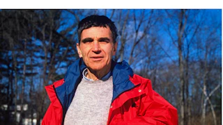 Harvard child psychologist Robert Coles standing outside, leaning against a wooden fence.