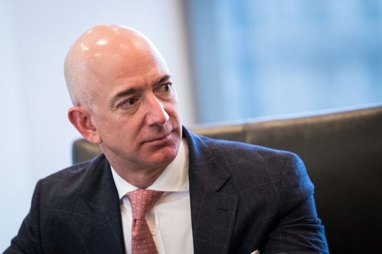 Jeff Bezos glances to his left as he sits at a table.