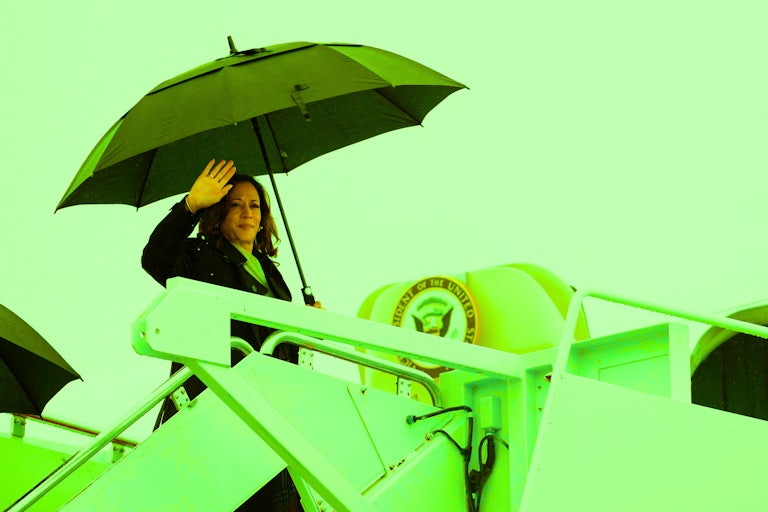 Kamala Harris holds an umbrella and waves as she boards the Air Force Two plane