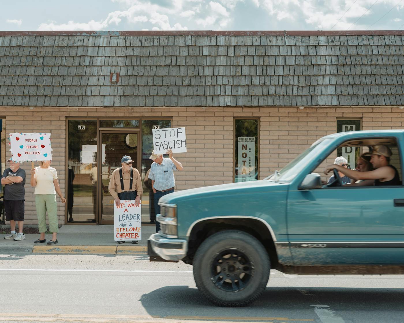Demonstrators hold signs along California Ave while other residents haze them from their vehicles during the No Kings rally in Libby, Montana on June 14