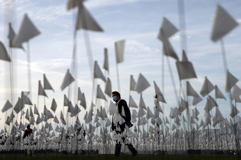 A man walks through a sea of flags on a lawn.