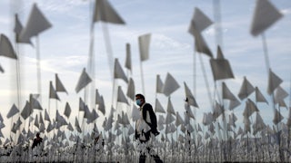 A man walks through a sea of flags on a lawn.