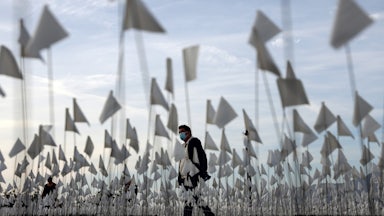 A man walks through a sea of flags on a lawn.