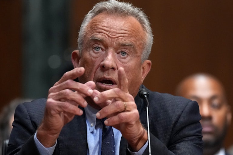 HHS Secretary RFK Jr. testifies before the Senate, holding up both hands for emphasis as he speaks.