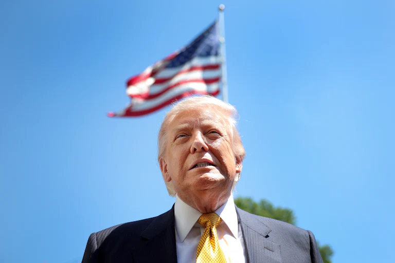 Donald Trump clenches his teeth together while standing in front of an American flag