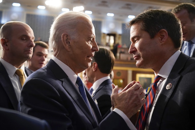 speak, standing very close to each other. Others are in the background.
