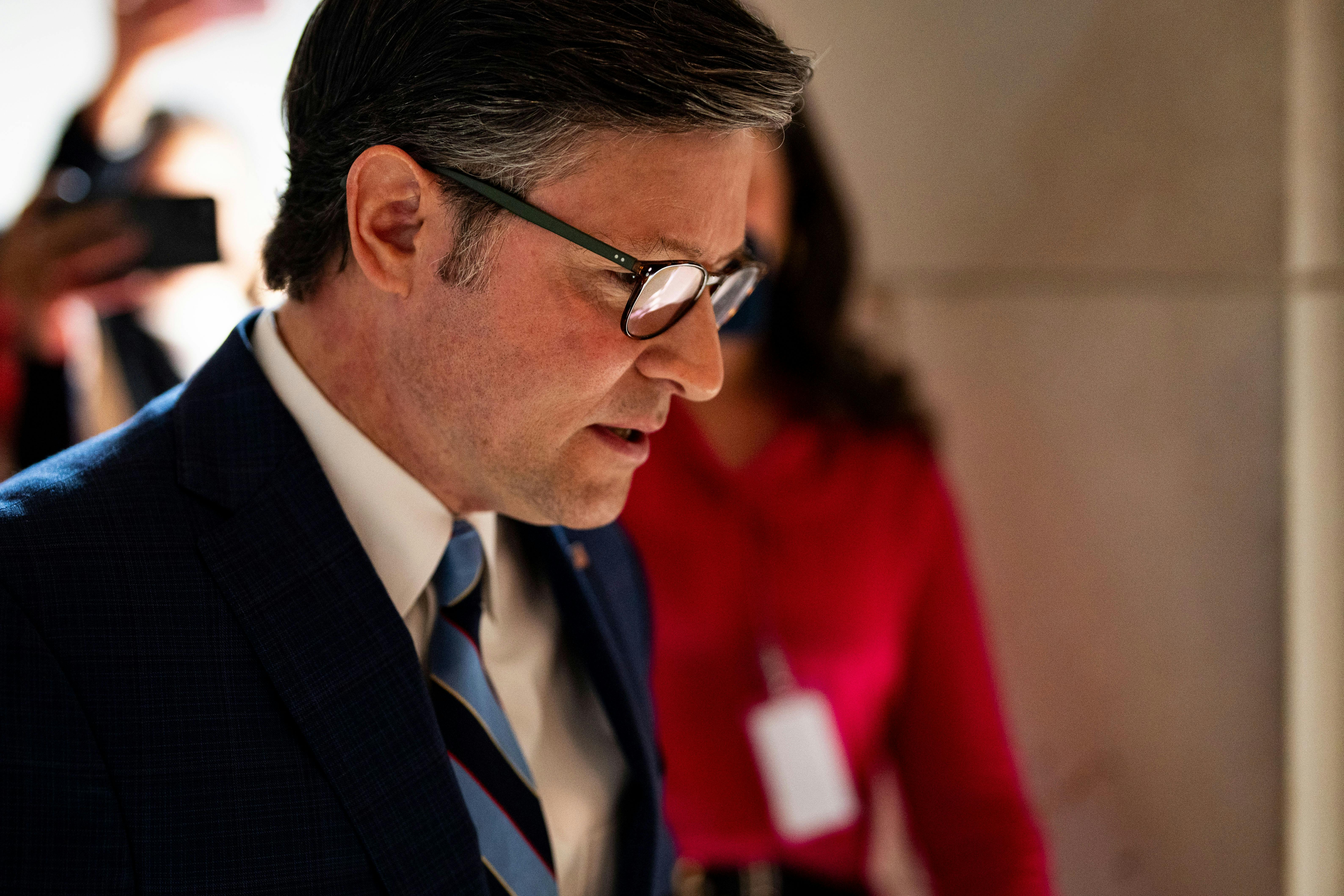 House Speaker Mike Johnson looks down while walking in the Capitol