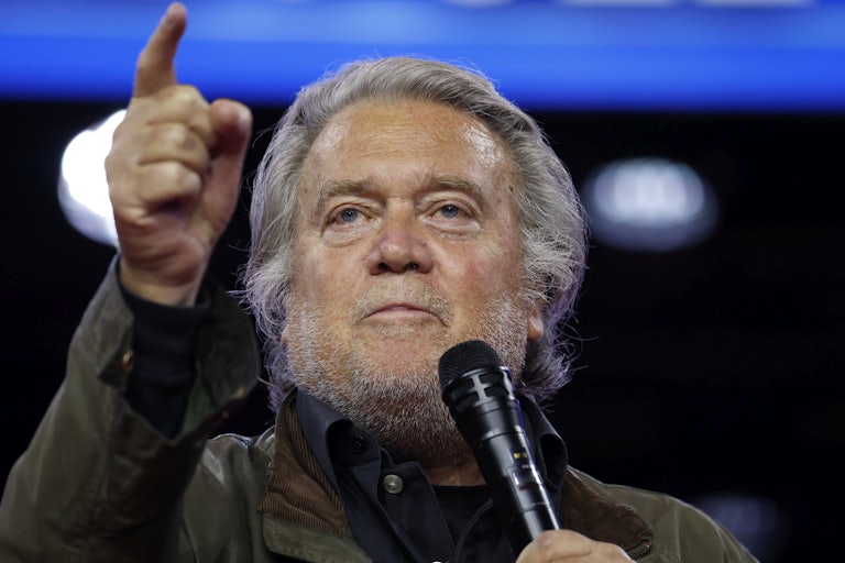 Steve Bannon points while holding up a microphone
