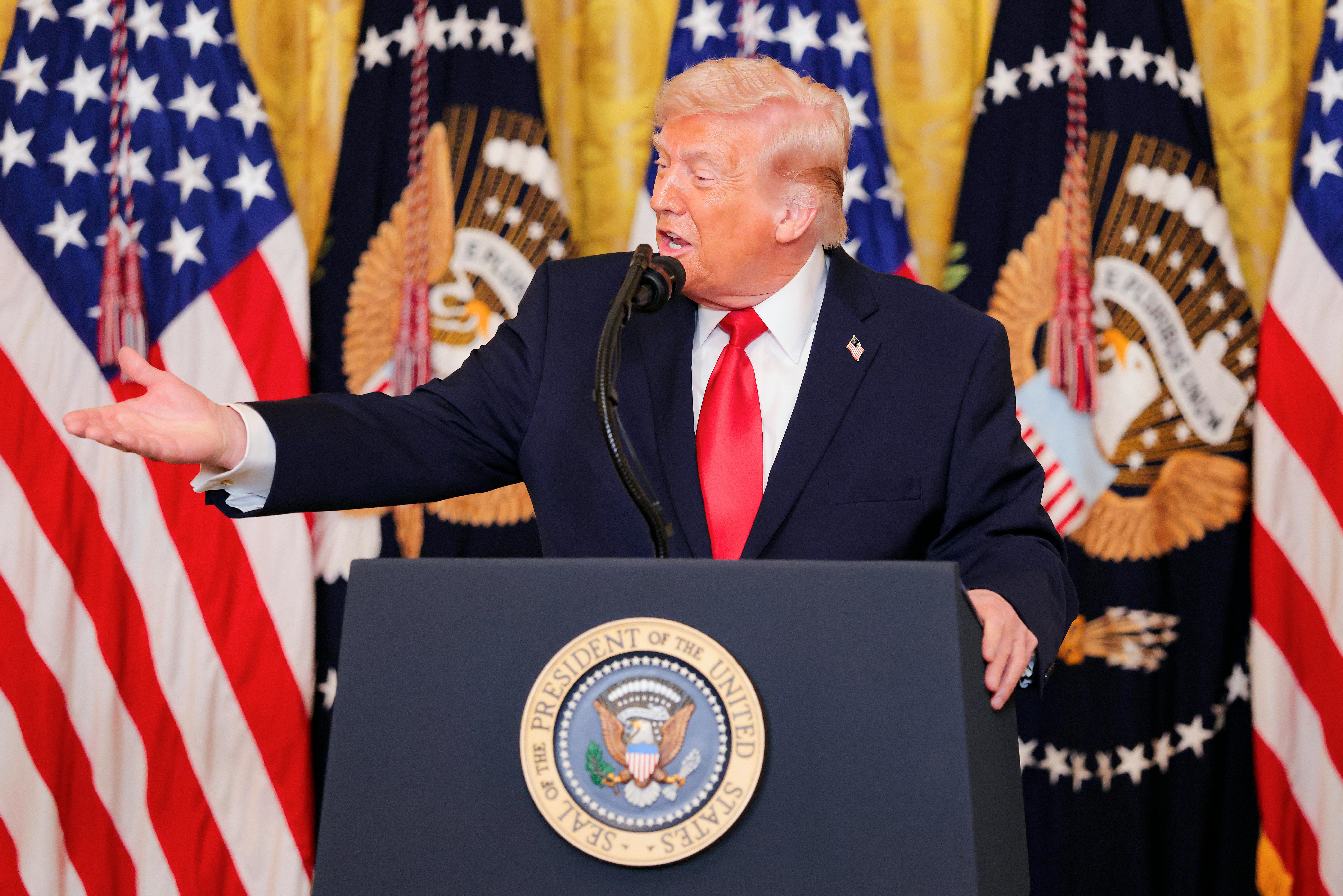 Donald Trump gestures while speaking at a podium 