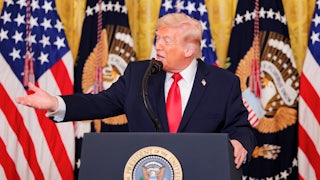 Donald Trump gestures while speaking at a podium