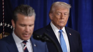 Donald Trump watches while Defense Secretary Pete Hegseth speaks at a podium