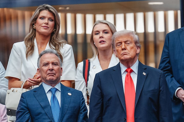Lindsey Halligan and Karoline Leavitt stand next to each other, while Steve Witkoff and Donald Trump stand in front of them.