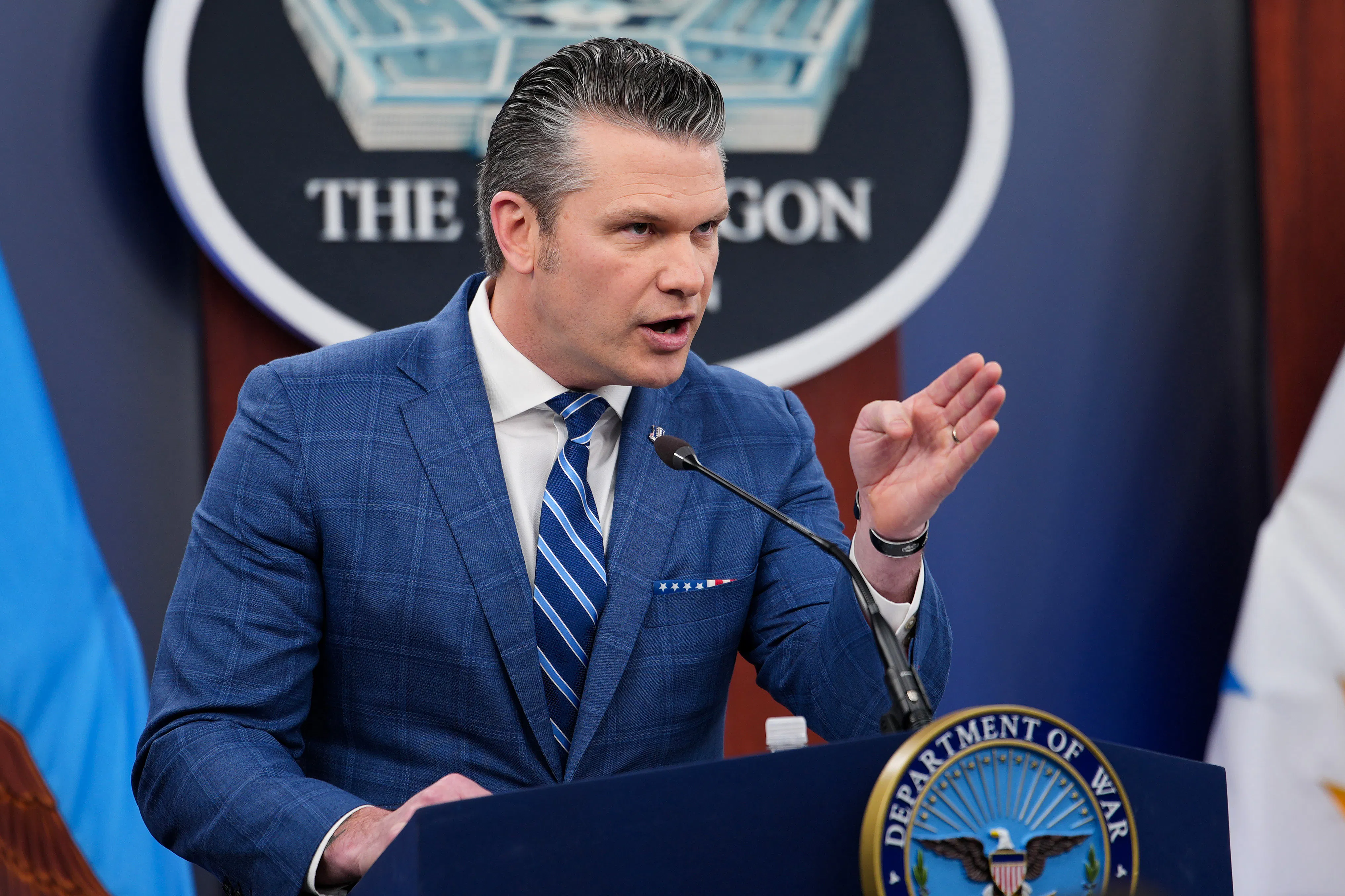 Defense Secretary Pete Hegseth points while standing at the podium