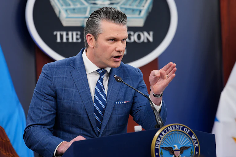 Defense Secretary Pete Hegseth points while standing at the podium
