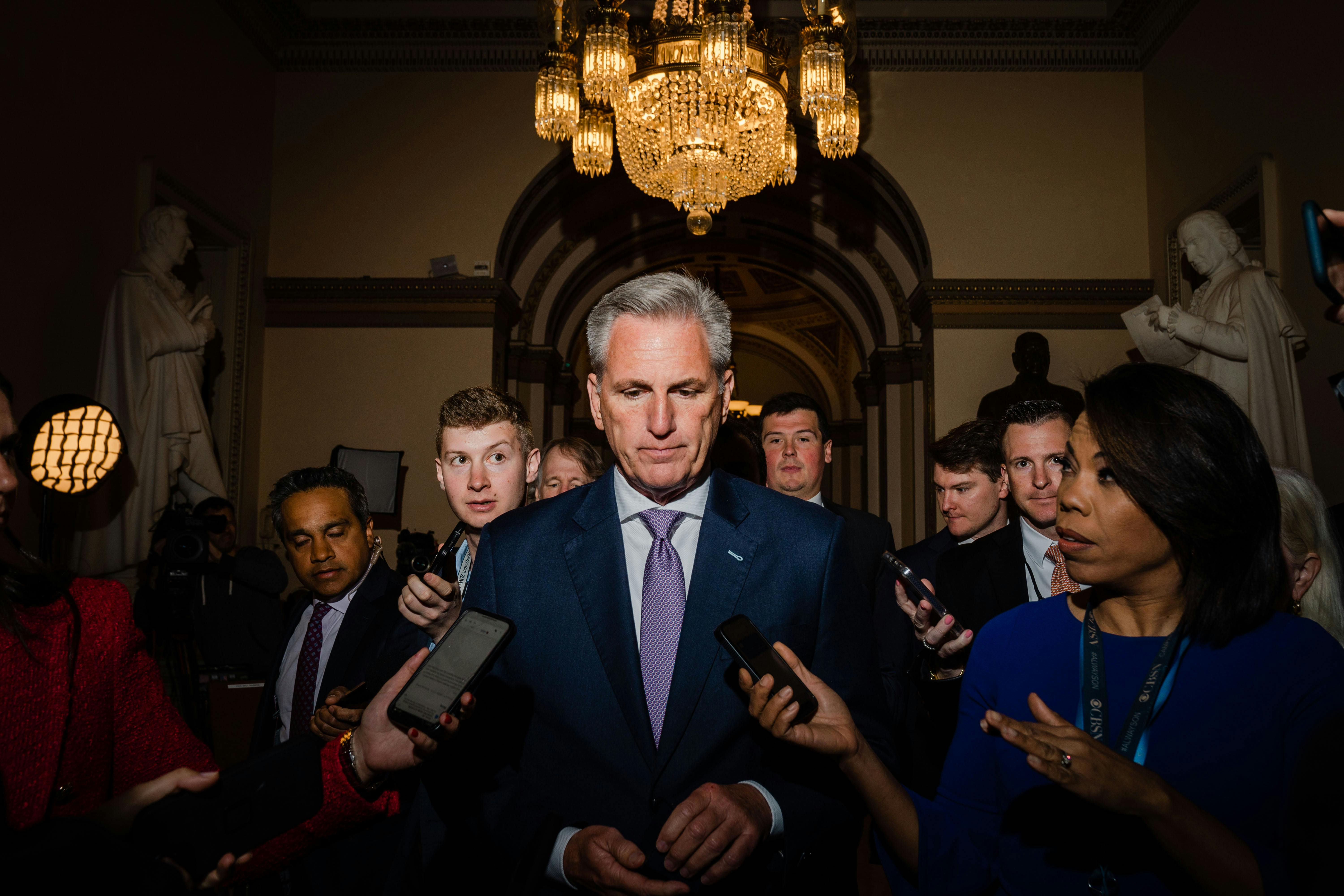 Kevin McCarthy walks, surrounded by reporters.