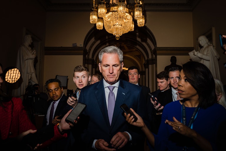 Kevin McCarthy walks, surrounded by reporters.